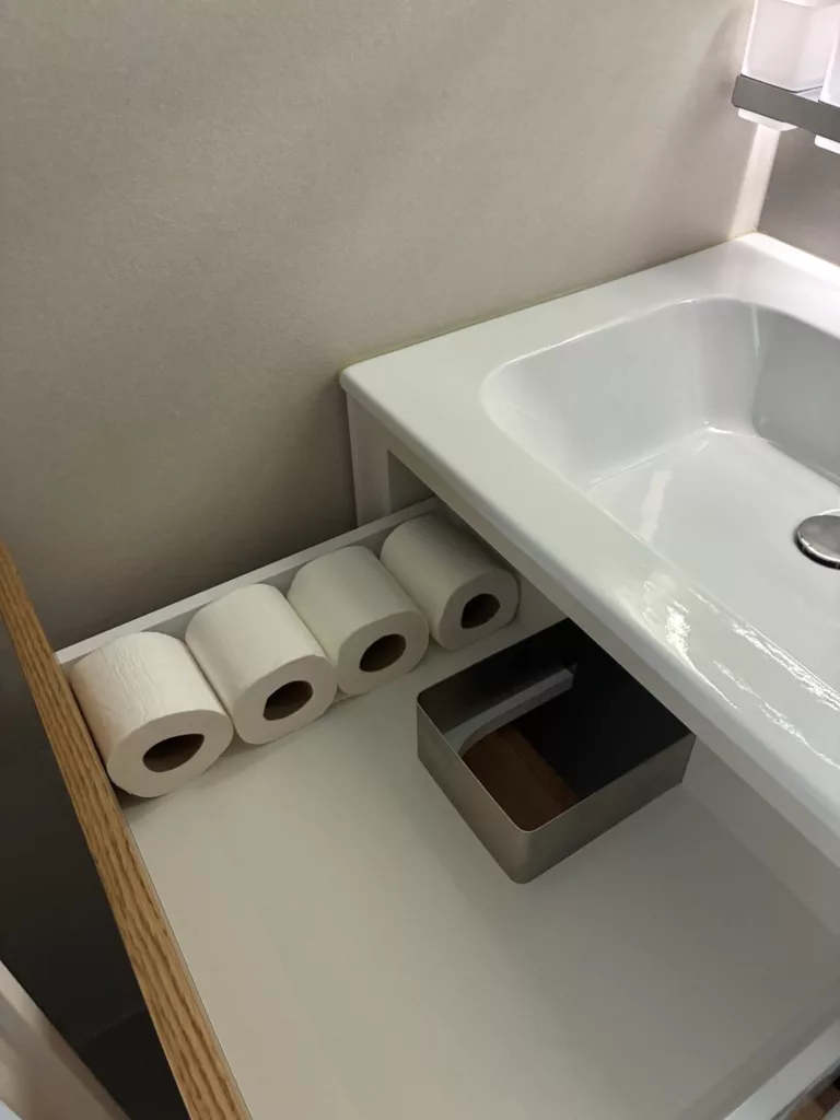 Consommables réapprovisionnés sous le lavabo d'un appartement Airbnb à Puidoux
