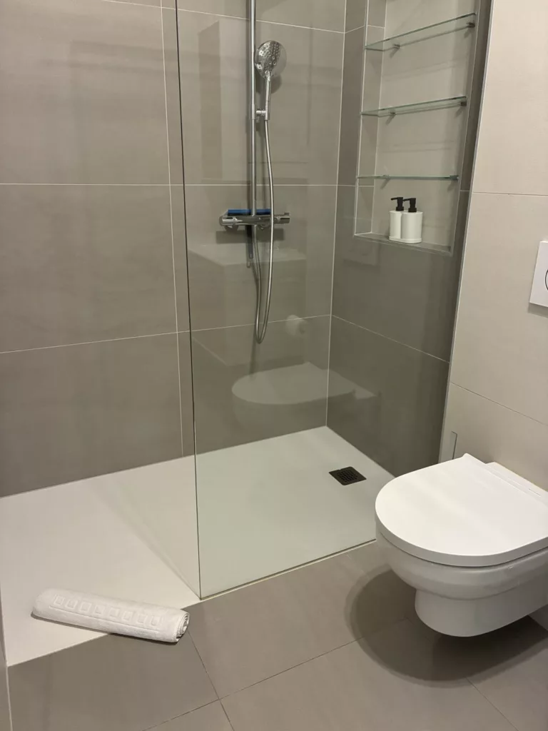 Salle de bain d'un appartement Airbnb à Puidoux après le nettoyage Raissi Nettoyage : douche à l'italienne, WC suspendu, serviette pliée